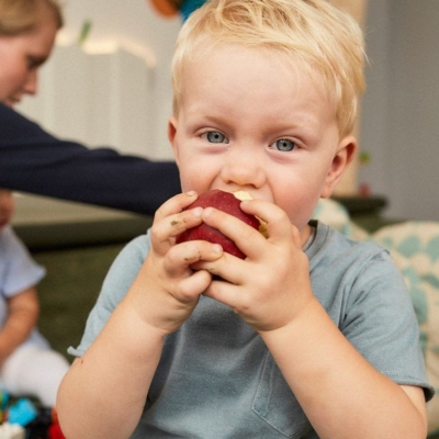 Krippenkind beißt in einen roten Apfel in der Kita kinderzimmer Hamburg