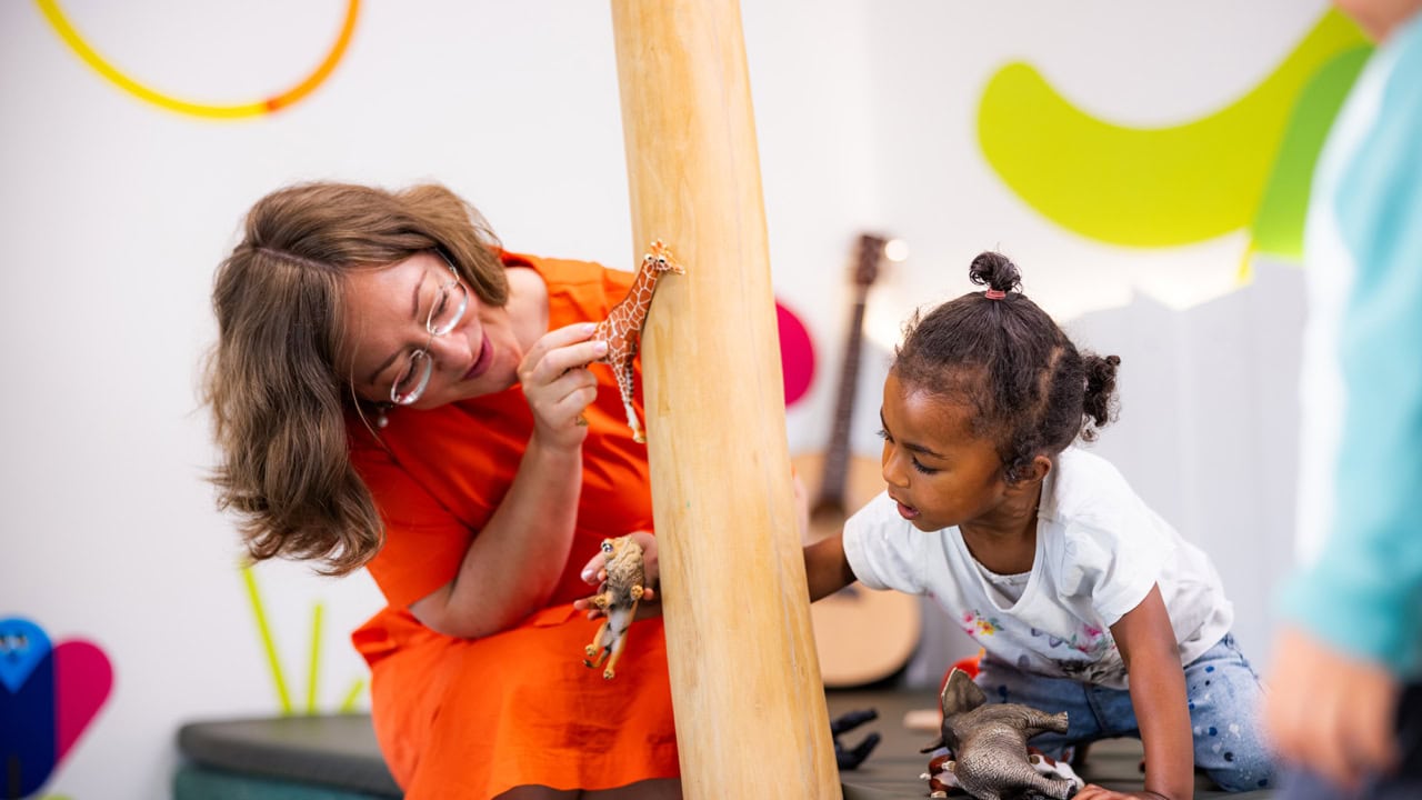 kita-kinderzimmer-hamburg-brand-shooting-olga-madchen-3x7a3789 Eine Pädagogin zeigt einem Kind eine Giraffe in der Kita kinderzimmer Hamburg