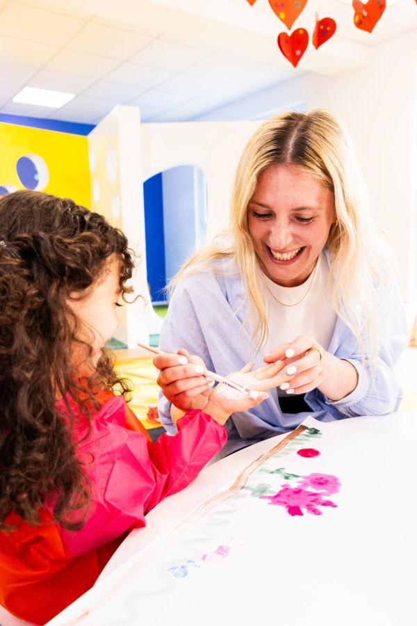 Pädagogin die einem Kind Fingerfarbe aufrägt in der Kita kinderzimmer Hamburg
