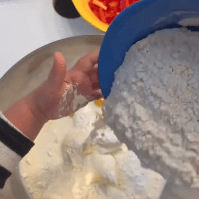 kita-kinderzimmer-eißendorf-hamburg-backen-herzhafter-kuchen-Bildschirmfoto 2024-11-12 um 10.39.13 Kinder fügen Mehl zum Kuchenteig hinzu in der Kita kinderzimmer Eißendorf in Hamburg Eißendorf