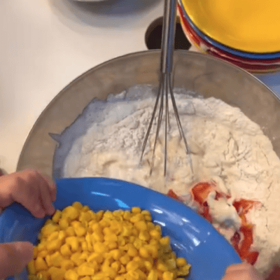 kita-kinderzimmer-eißendorf-hamburg-backen-herzhafter-kuchen-Bildschirmfoto 2024-11-12 um 10.39.31 Kinder fügen Mais zum Kuchenteig hinzu in der Kita kinderzimmer Eißendorf in Hamburg Eißendorf