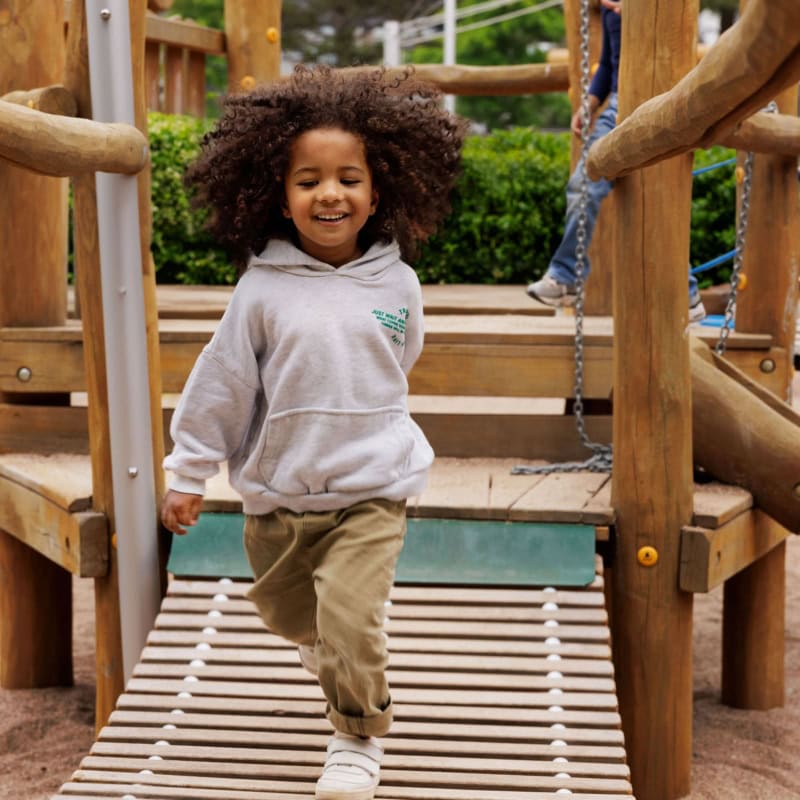 Junge läuft auf Spielplatz fröhlich auf Kamera zu