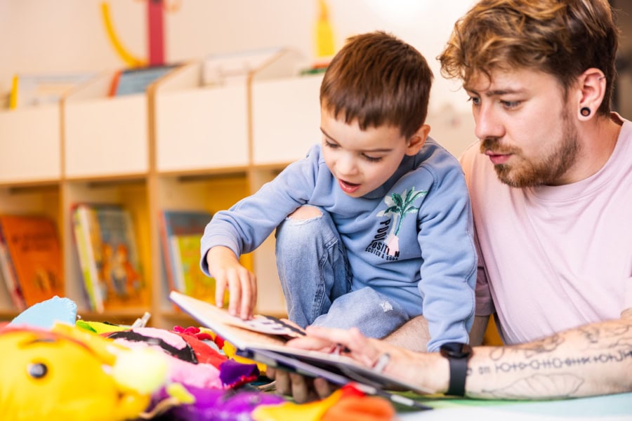 kita-kinderzimmer-hamburg-brand-kjell-kind-vorlesen Pädagoge liest einem Jungen aus Buch vor