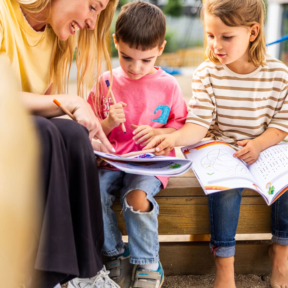 vorschule-kita-kinderzimmer-hamburg-kita-motiv-3X7A7096 Zwei Vorschulkinder aus der Kita kinderzimmer Hamburg lösen gemeinsam mit einer Erzieherin auf einem Klettergerüst Vorschulaufgaben aus einem Heft