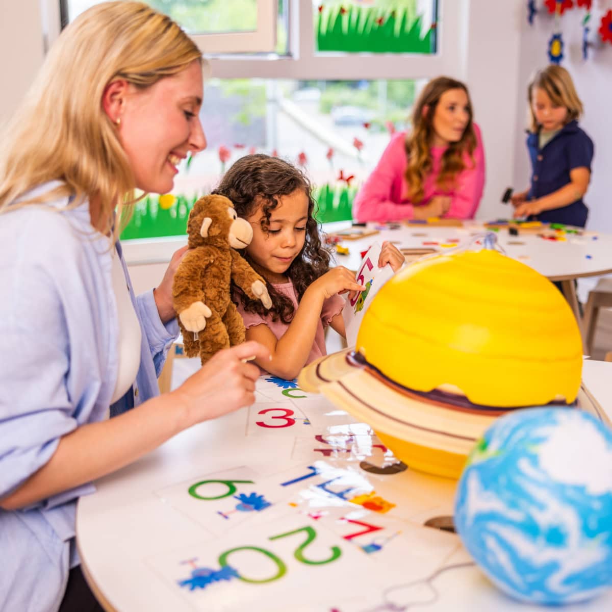 vorschule-kita-kinderzimmer-hamburg-kita-motiv-X7A5802 Eine Erzieherin zeigt einem Vorschulkind verschiedene Planeten in der Kita kinderzimmer Hamburg