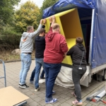 kita-kinderzimmer-hamburg-spende-cubes-hbg 4 Personen verladen Arbeitscubes auf Anhänger vor der Kita kinderzimmer Hamburg