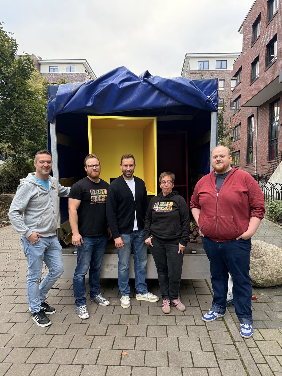 kita-kinderzimmer-hamburg-spende-cubes-hbg2 5 Personen stehen vor einem beladenen Anhänger vor der Kita kinderzimmer Hamburg